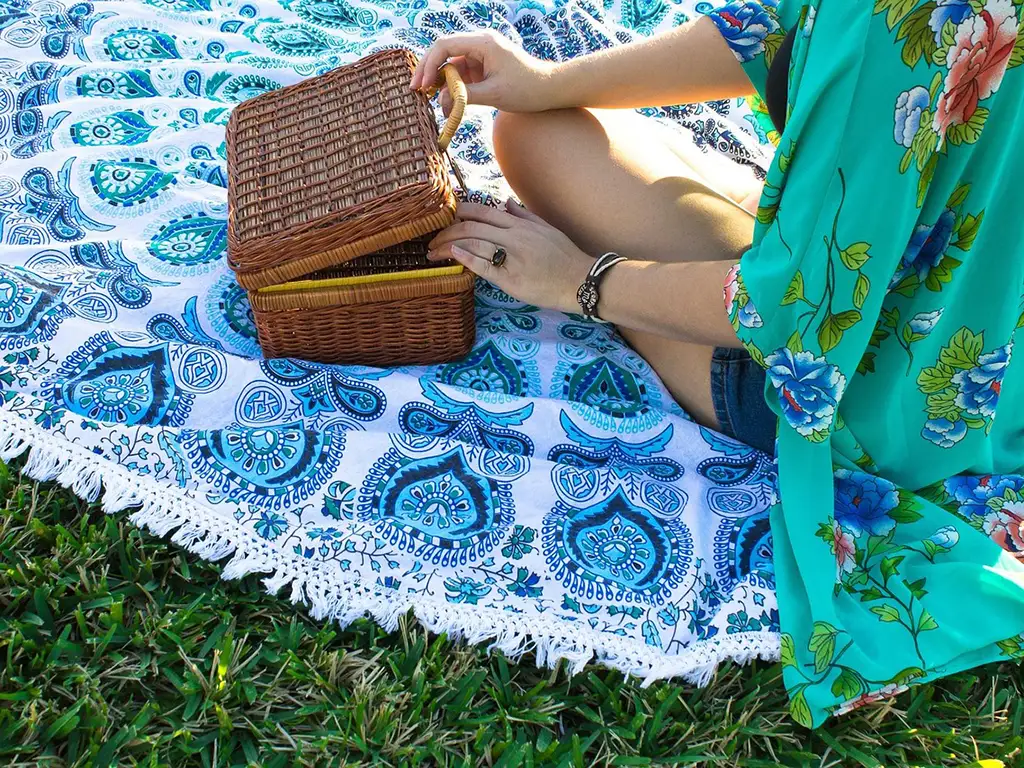Eine Frau öffnet einen Picknickkorb auf einer Decke auf einer Wiese