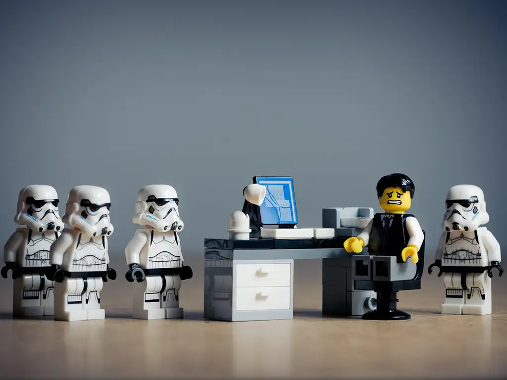 Lego-Figuren und eine Schreibtischszene vor grauem Hintergrund
